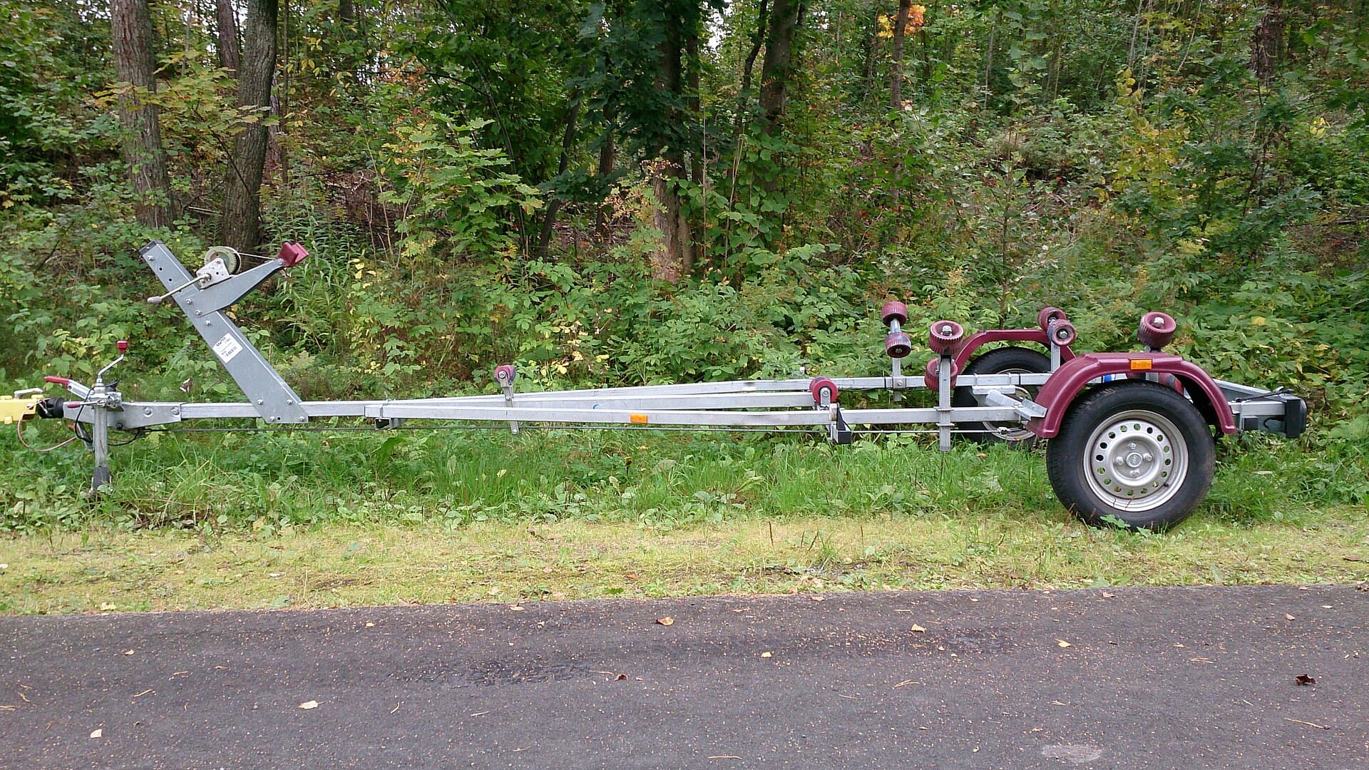 Fibreglass boat sitting on a dual-axle trailer with visible rollers and winch post
